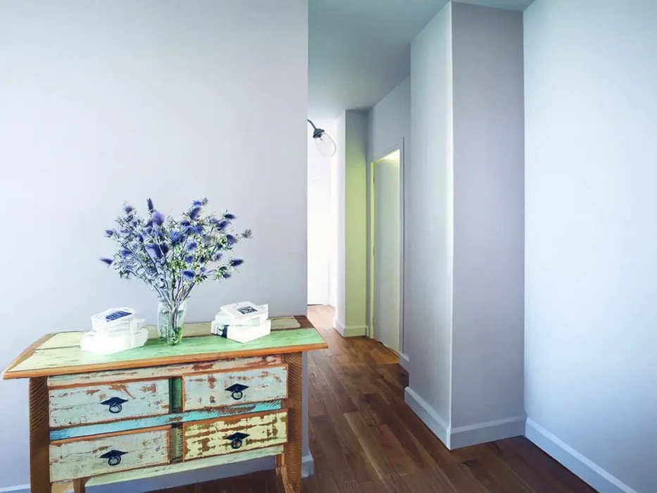 Intérieur résidentiel moderne avec meuble vintage restauré, vase de fleurs bleues, objets décoratifs blancs sur plateau vert