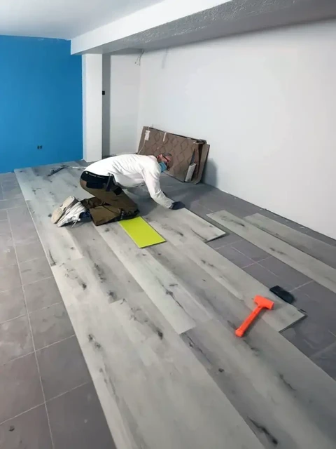 Ouvrier installant un parquet flottant dans une chambre en rénovation