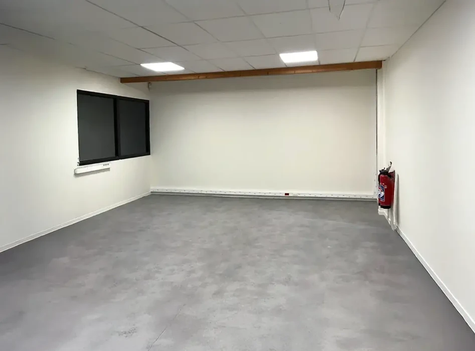 Salle vide récemment rénovée avec murs blancs et sol en revêtement PVC gris