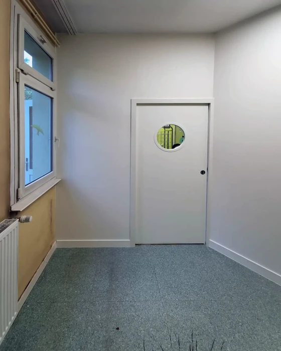 Salle vide récemment rénovée avec murs blancs et sol en revêtement PVC gris