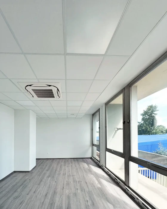 Intérieur d'appartement en cours de rénovation avec parquet en bois foncé fraîchement posé, murs blancs repeints, plafond avec faux-plafond et éclairage LED intégré