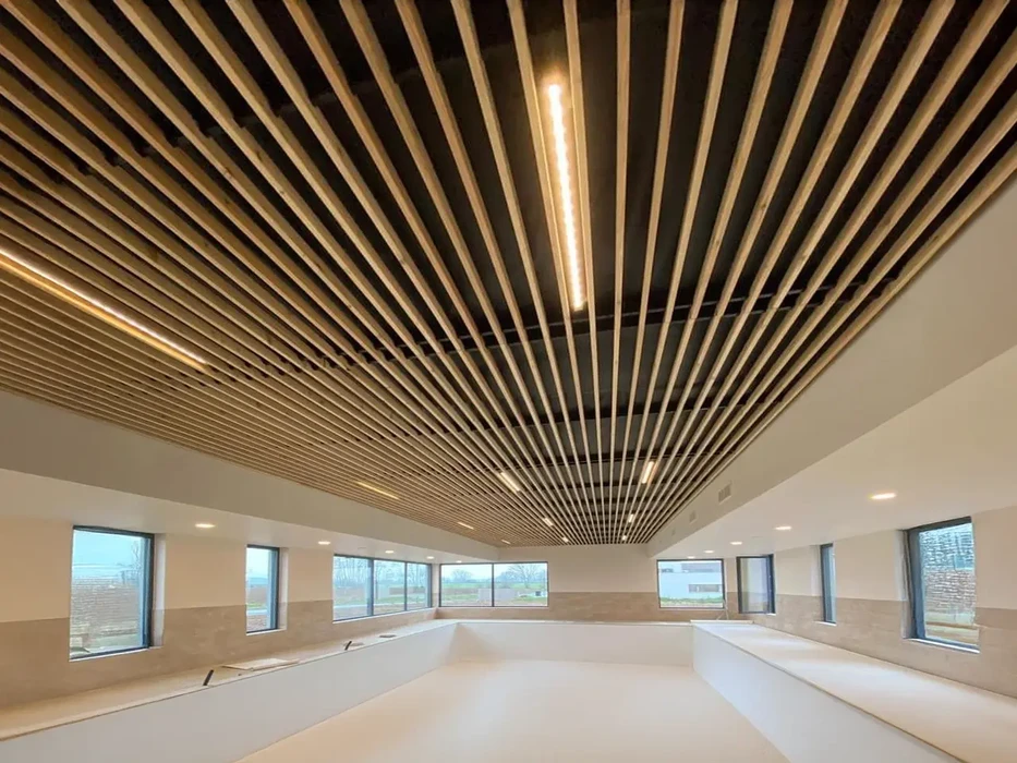 Technicien en tenue de sécurité réfléchissante installe une cloison coulissante dans un espace commercial avec murs jaunes