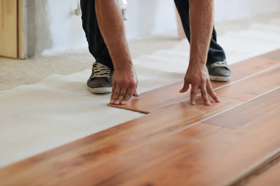 Artisan professionnel installant un parquet en bois massif dans une pièce intérieure