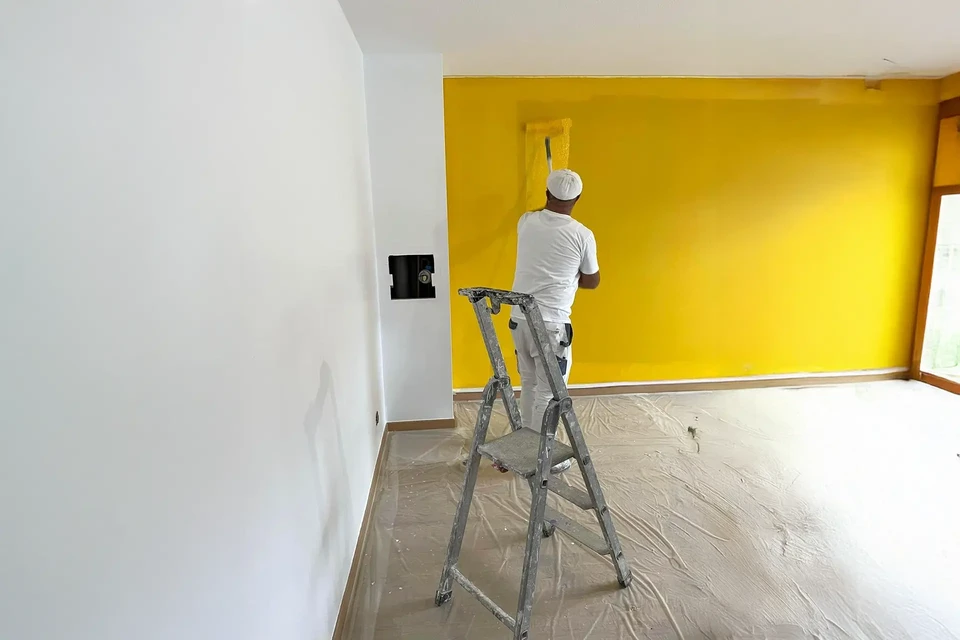 Chantier de rénovation extérieure avec ouvriers en vestes haute visibilité jaunes sur échafaudages métalliques