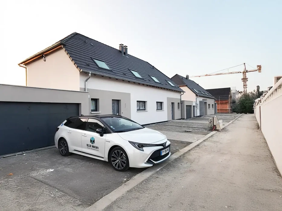 Scène extérieure d'un chantier résidentiel avec maisons neuves à toiture ardoise et façades blanches