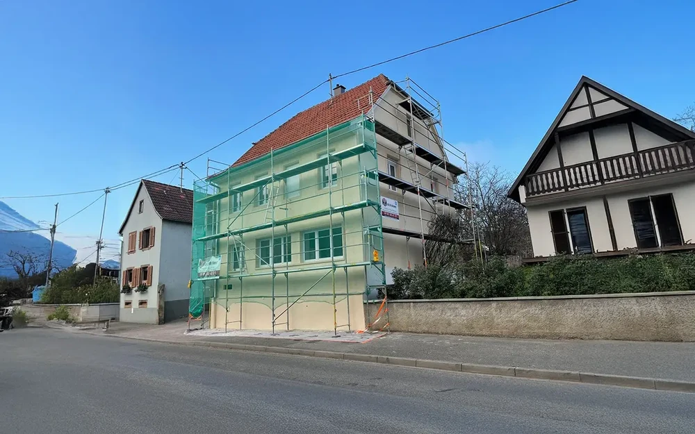 Peintre professionnel appliquant de la peinture murale bleue dans une pièce en rénovation, utilisant un escabeau aluminium